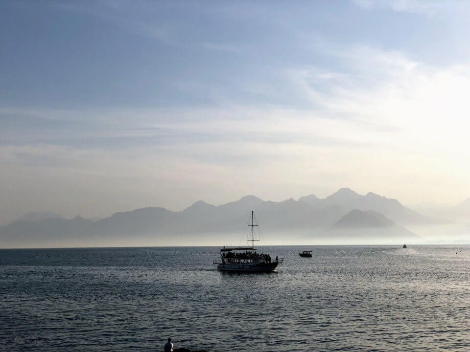 Vast body of water with single boat and mountains on the horizon