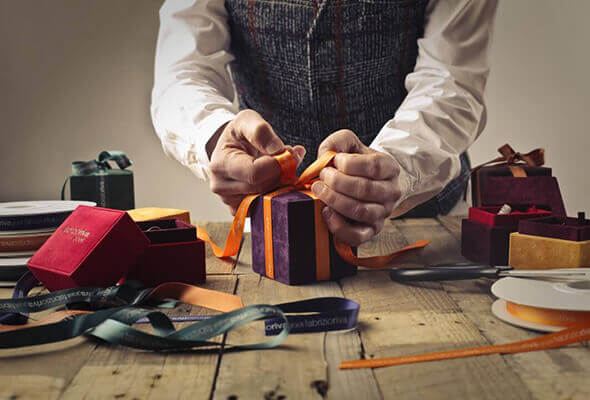 Person hand tying a bow on small wrapped gift